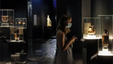 EPA A visitor wearing a protective mask looks on Ancient Greek artefacts exhibited at National Archaeological Museum in Athens, Greece, 14 May 2021