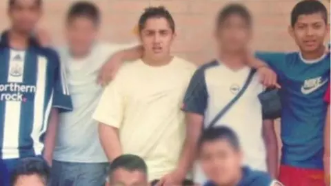Handout A group photo of young men in school. Akeel Nanabawa is standing in the middle wearing a cream top, Ruman Hussain in on the right wearing red shorts and a blue Nike top.