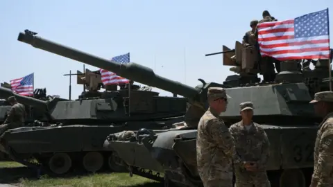 Getty Images US soldiers stand by Abrams Battle Tanks bearing the US flag prior to the opening ceremony of the joint multinational military exercise "Noble Partner 2017"