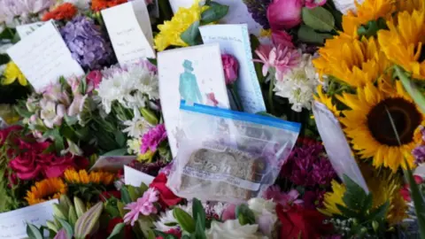 PA Media Floral tributes with a marmalade sandwich