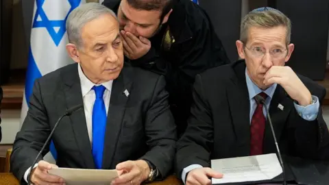 EPA An aide whispers into the ear of Benjamin Netanyahu during a cabinet meeting