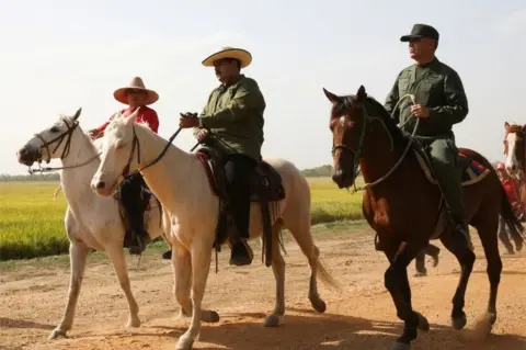 Reuters Venezuela"s President Nicolas Maduro (C) and Venezuela"s Defense Minister Vladimir Padrino Lopez (R) ride horses, during a visit to planting fields in Calabozo, Venezuela April 5, 2017.