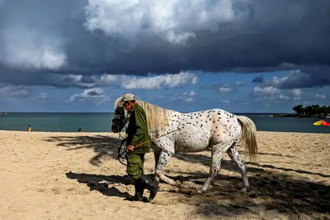 Yamil Lage / AFP A man walks with his horse at Bacuranao beach in Havana province, Cuba