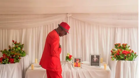 Getty Images A former wrestler and a journalist at the Congolese National Radio Television, Maitre Satonge, pays tribute to his former colleague and friend, Democratic Republic of Congo's wrestling champion Alphonse Mwimba Makiese, during a memorial service for Alphonse Mwimba Makiese, at the Mwimba residence, in Kinshasa on September 4, 2020.