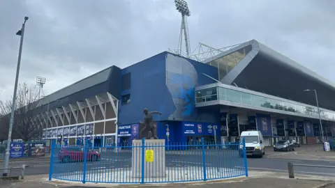 Alice Cunningham/BBC A general view of the outside of Portman Road stadium. Vehicles pass on the roads directly outside the stadium.