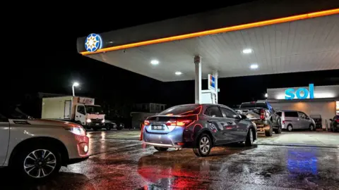  CHANDAN KHANNA/AFP via Getty Images Cars queueing at a petrol station in the dark