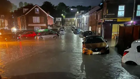 Michael Ford Cars are submerged in flood water on a residential street