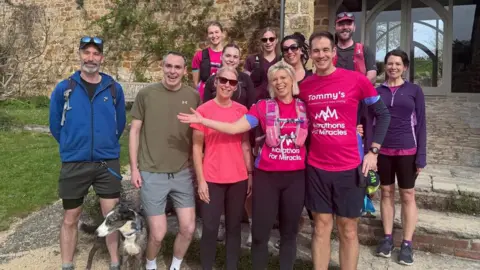 Alice Draper A group of smiling people, some in running gear, look at the camera
