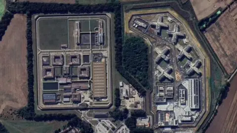 Google Ariel view looking down on HMP Full Sutton. There is a large assortment of buildings arranged in squares and crosses surrounded by straight fences.