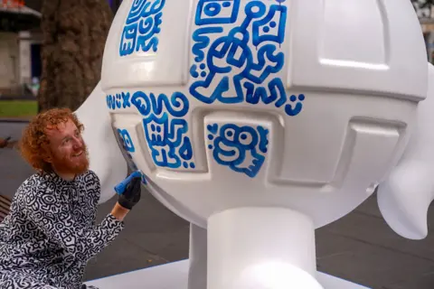 Art of London Mr Doodle draws on one of his sculptures in Leicester Square using a blue marker pen.