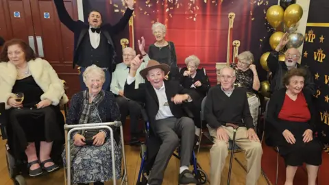 Residents who star in the film cheer for a photo with the producer James Dixon 