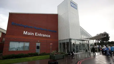 Getty Images A general view of Birmingham Heartlands Hospital in Birmingham. It is a big building with a large NHS logo at the top. It has a grass frontage. Some people can be seen walking from the car park inside the hospital.