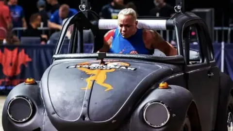 Sue Taylor-Franklin Sue Taylor-Franklin carrying a car as part of a competition