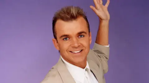 Wayne Dobson in his 1990s heyday wearing suit jacket and spiky hair