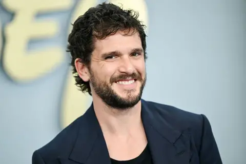 Variety via Getty Images Kit Harrington seen smiling on the red carpet in a blue blazer on the red carpet in New York in May.