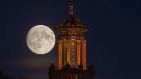 Matt Cardy/Getty Images The large bright supermoon is seen behind the Beckford's Tower in Bath at night. The tower is illuminated by floodlights and the landmarks on the surface of the moon are visible