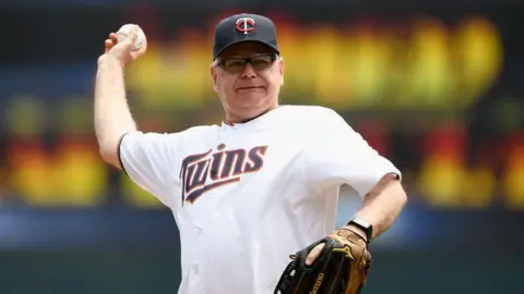 Getty Images Tim Walz throwing a ball at a baseball game