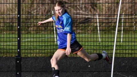 Huish Tigers A teenage girl about to take a corner kick on a football pitch