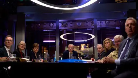 Sky A group of people around a table in a dimly lit room 