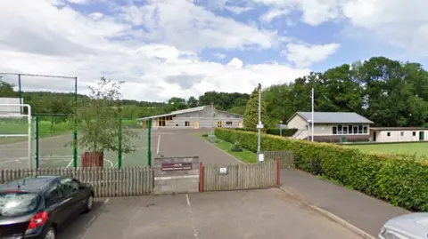 Newtown St Boswells Primary School in the distance behind a gate with a playground in front of it