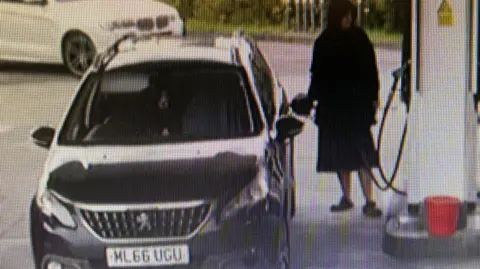 Police Scotland A CCTV image of a woman filling a car with petrol