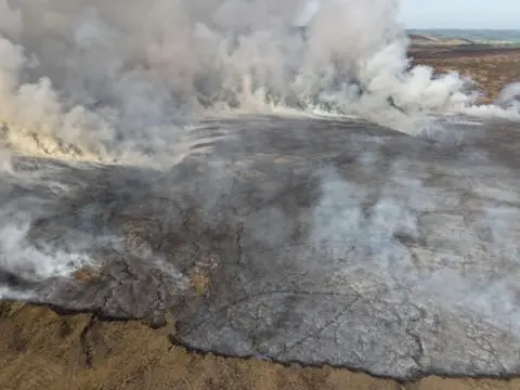 Derby Mountain Rescue Team A drone shot taken above the wildfire, showing a large area of black ground and smoke.