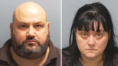 Custody photos of Richard Elkin and Hayley Bell. He is bald with a greying beard and a ring through his nose. She has black hair over her shoulders, a fringe and also has a ring through her nose.
