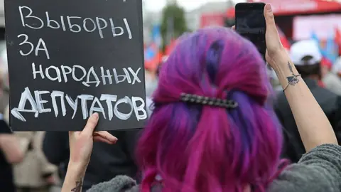 Getty Images A woman with her back to camera holds a sign, with text in Russian.