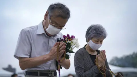 EPA An elderly couple prays for victims in front of a cenotaph at Peace Memorial Park in Hiroshima