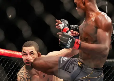 Getty Images Israel Adesanya of Nigeria kicks Robert Whittaker of Australia in their middleweight championship fight during UFC 271 at Toyota Center in Houston, Texas, the US - Saturday 12 February 2022