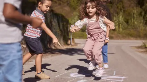 Getty Images Children playing hopscotch in the street