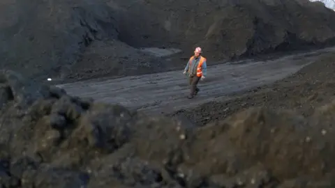 Reuters A worker walks past coal piles at a coal coking plant in Yuncheng, Shanxi province