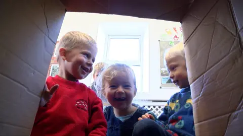 Children looking inside cardboard box