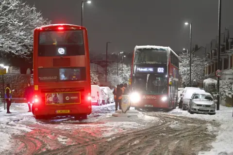 Dave J Hogan / Getty Images Two buses stuck in snow in Muswell Hill, London