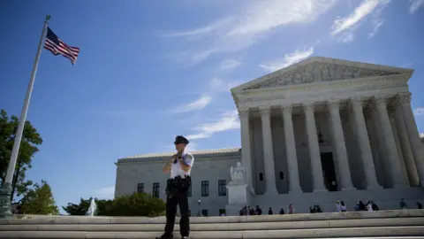 Getty Images A police officer is seen outside the US Supreme Court after it was announced that the court will allow a limited version of President Donald Trump's travel ban to take effect June 26, 2017 in Washington, DC. T