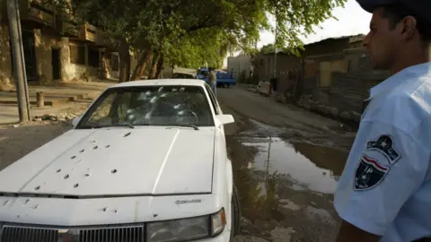 Getty Images An Iraqi policeman stands by the bullet riddled car of two women shot dead by private security guards in Baghdad, 9 October 2007