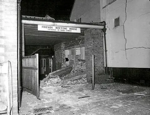 HM Coroner Pub brick wall that has collapsed into the neighbouring car port