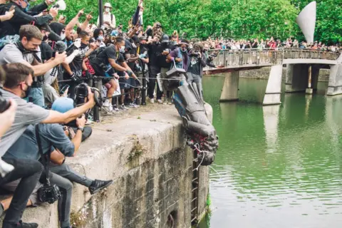 Giulia Spadafora/NurPhoto via Getty Image The statue of Colston is pushed into the River Avon. Edward Colston was a slave trader of the late 17th century who played a major role in the development of the city of Bristol, England, on 7 June 2020.