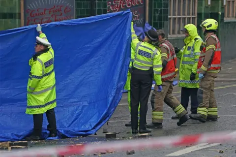 PA Media Police officers and firefighters erect tarpaulin