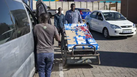 Getty Images Man loading goods into a minibus