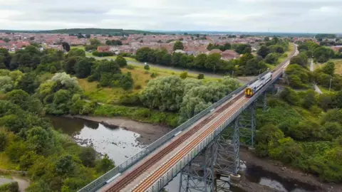 Northern A train crosses a bridge over a river