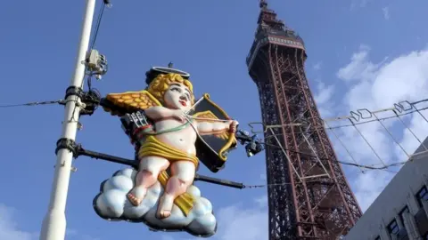 Cupid is seen as a rather gaudy light on the Blackpool Illuminations, with Blackpool Tower in the background