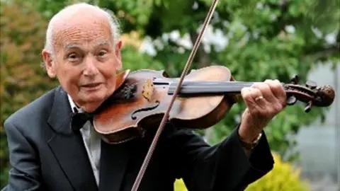 Gloucestershire Academy of Music Trevor Pleass playing his violin in his garden