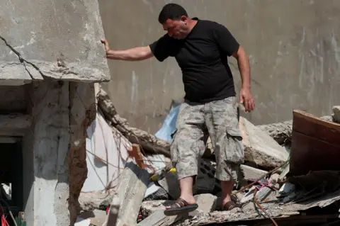 Reuters Syrian refugee Ahmed Staifi walks among the debris of a house were his wife and two of his daughters were killed following an explosion in Beirut, Lebanon (11 August 2020)
