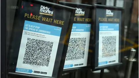 Getty Images Track and trace QR codes are displayed outside a pub, in Manchester, north west England in October, 2020