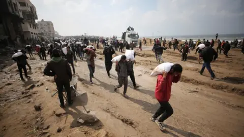 Reuters Palestinians carry bags of flour they took from an aid convoy