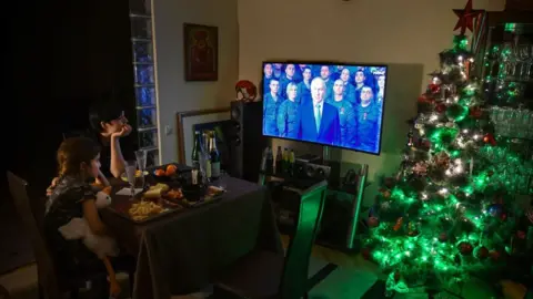 Getty Images A family watches President Putin's speech