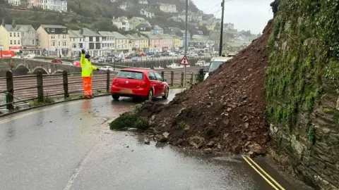 Armand Toms Cormac worker directs traffic around landslip in Looe