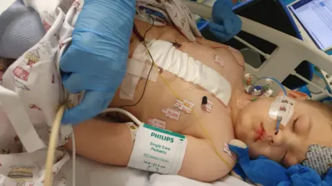 Family photo Brayden Bull lying in hospital bed