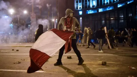 Getty Images Protester carries a Peruvian flag during clashes in Lima on 14 November 2020